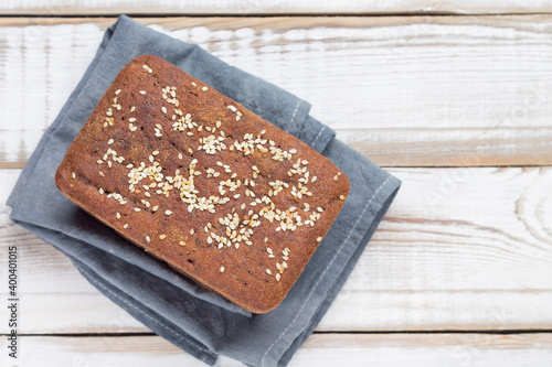 Freshly baked sourdough bread made from rye flour on a gray linen napkin, with sesame seeds. Natural light background.