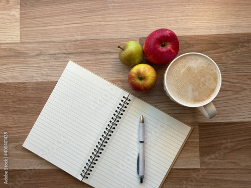 Desktop with pen, notebook, apples and coffee