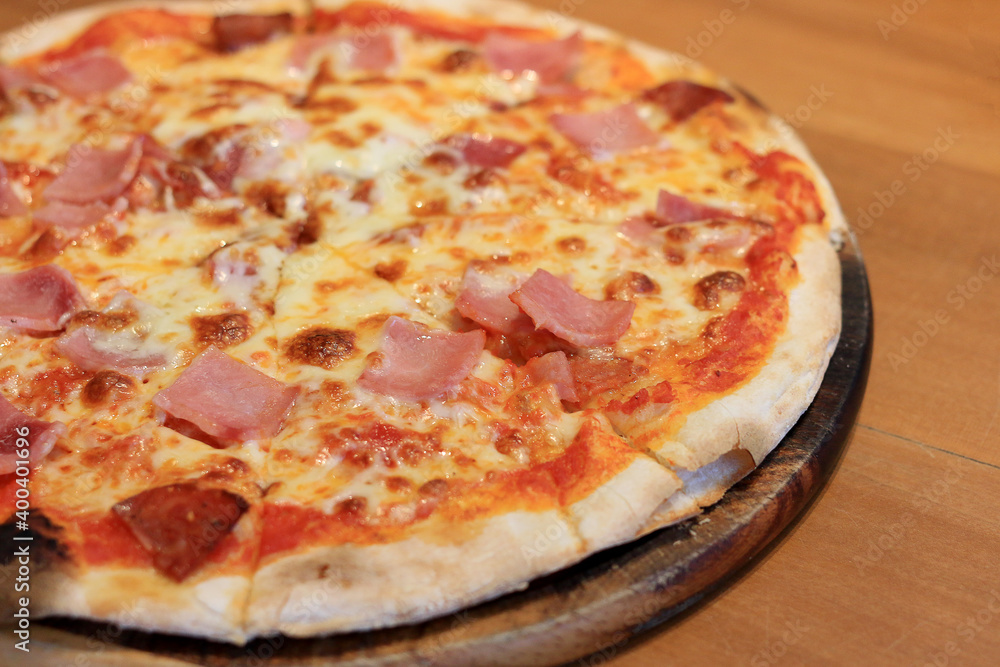 Sliced cheesy pizza on wooden cutting board.Delicious Italian food delivered in cardboard box for lunch meal.Crusty thin dough baked in oven with tasty parmesan,gorgonzola,mozzarella,ham and cheese Sliced cheesy pizza on wooden cutting board.Delicious Italian food delivered in cardboard box for lunch meal.Crusty thin dough baked in oven with tasty parmesan,gorgonzola,mozzarella,ham and cheese