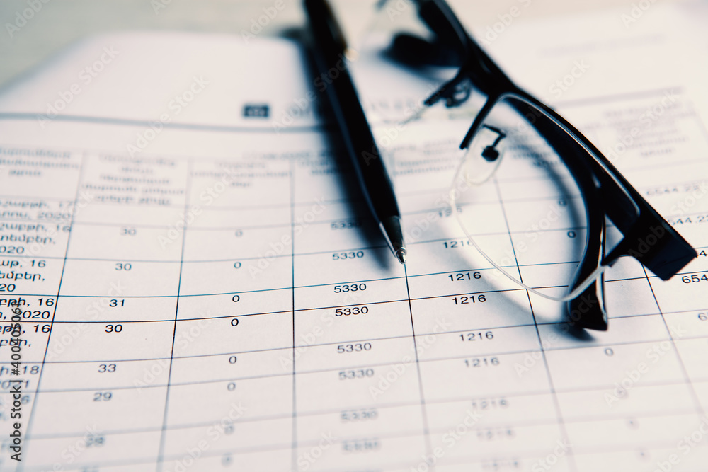glasses with pen close up and financial report - accounting concept glasses with pen close up and financial report - accounting concept