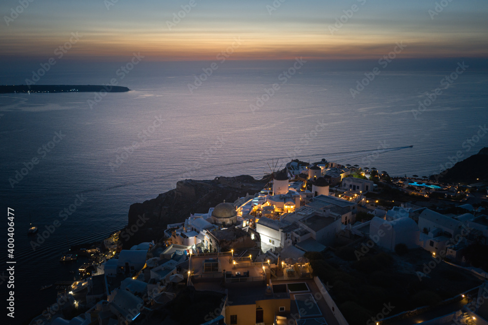 Fototapeta premium Oia town on Thira. Santorini island with colorful volcanic cliffs and deep blue sea aerial view