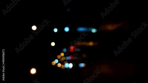 Vertical video blurry cars driving along city road at night. Abstract video, street of a night city and cars moving along with headlights, defocused video with bokeh effect.