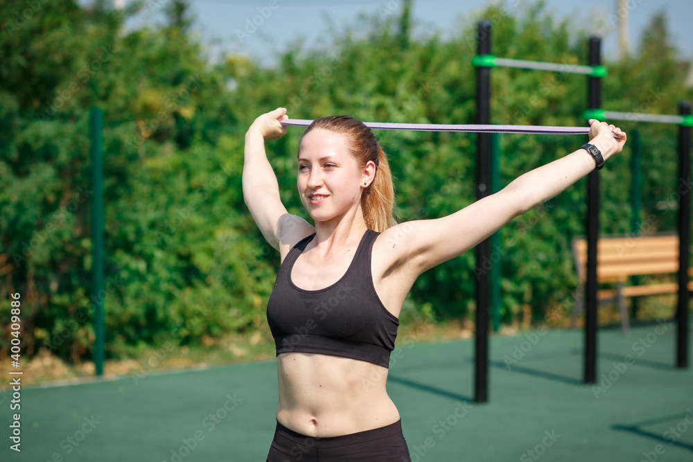 Training on the street, a young female athlete makes a workout on the street platform. Female athlete warms up before training on a treadmill, stretching on a rubber stadium Training on the street, a young female athlete makes a workout on the street platform. Female athlete warms up before training on a treadmill, stretching on a rubber stadium