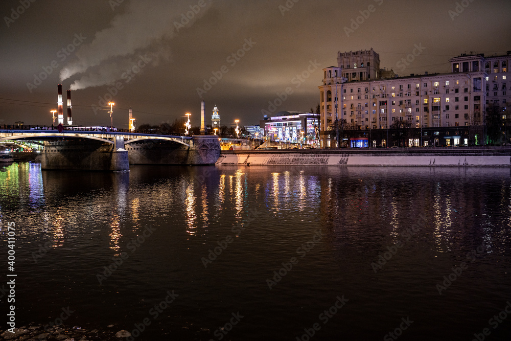 evening winter cityscape with river bridge and illuminated buildings