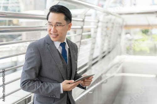 Portrait asian business man business district ,senior visionary executives leader with business vision , tabled phone computer in hand - lifestyle business people concept