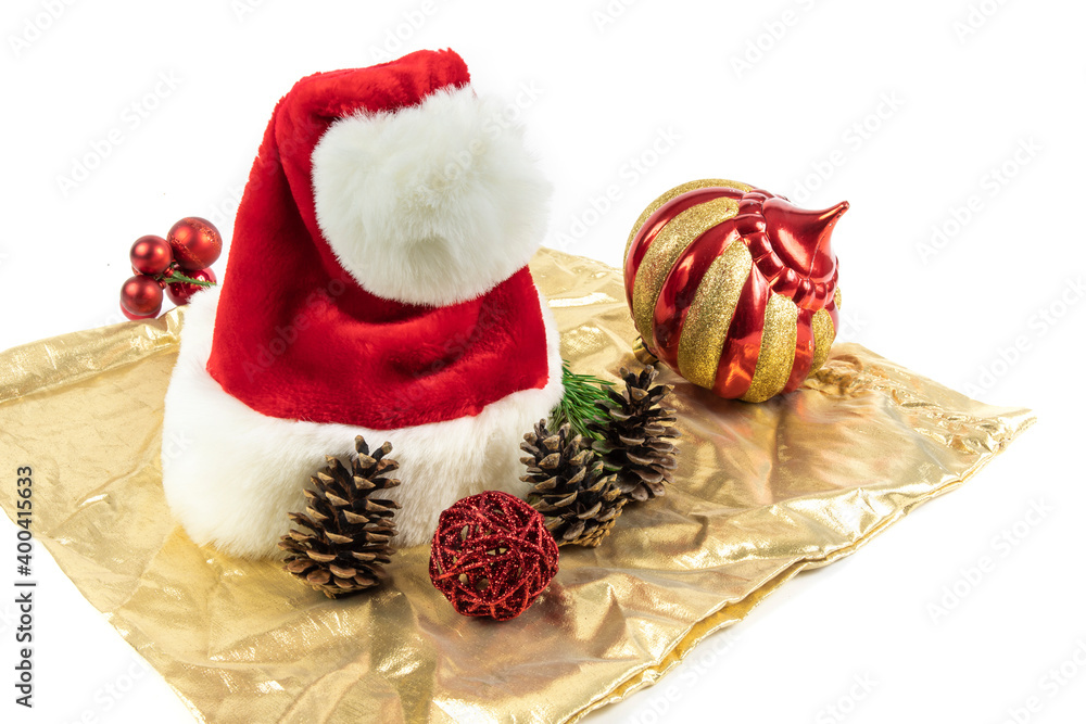 a red Santa Clause hat with Christmas decorations on a gold colored satin cloth a red Santa Clause hat with Christmas decorations on a gold colored satin cloth