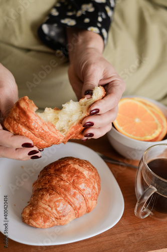 woman having breakfast in bed coffee and croissant