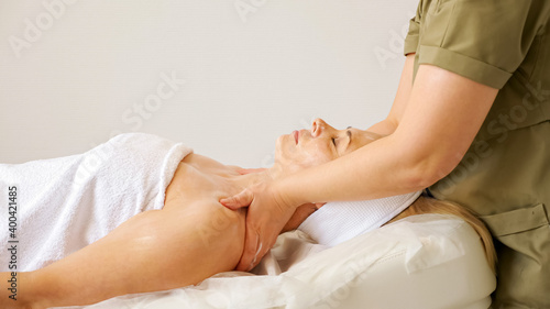 Quadro em tela Experienced cosmetologist massages woman bare shoulders and neck lying on large