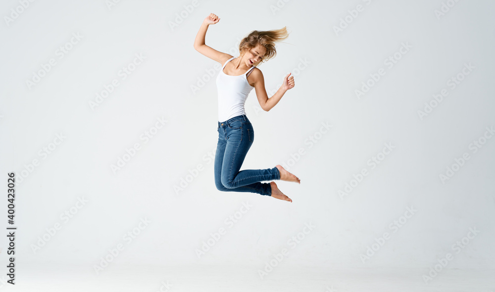 Fototapeta premium woman jumped up on a light background in full growth sport fitness