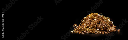 Scrap gold jewelry on black background. Wide horizontal banner with empty copy space for text.