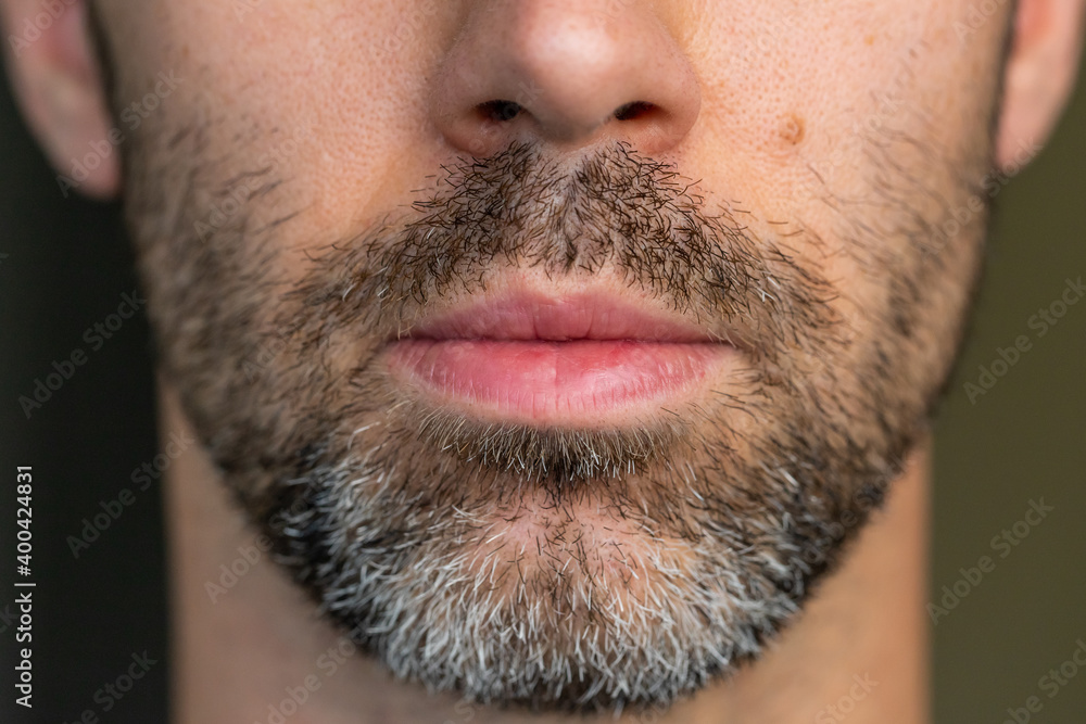 A young Caucasian man with brown and white facial hair with a serious look. Shallow depth of field. A young Caucasian man with brown and white facial hair with a serious look. Shallow depth of field.