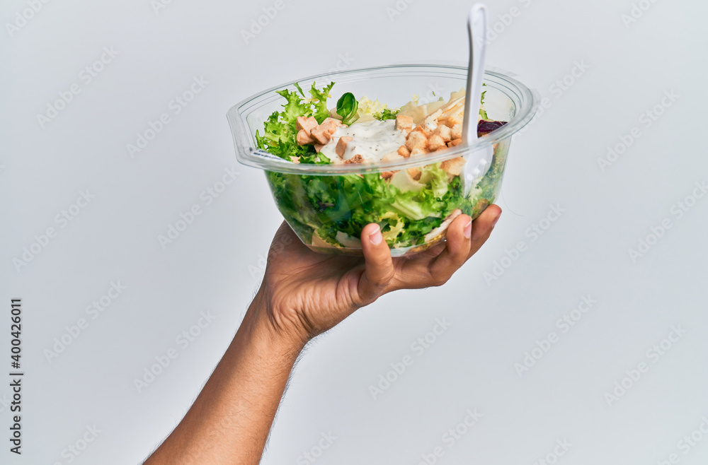 Hand of hispanic man holding bowl with salad over isolated white background.