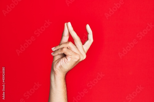 Arm of caucasian white young man over red isolated background snapping fingers for success, easy and click symbol gesture with hand photo
