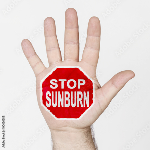 On the palm of the hand there is a stop sign with the inscription - STOP SUNBURN. Isolated on white background.