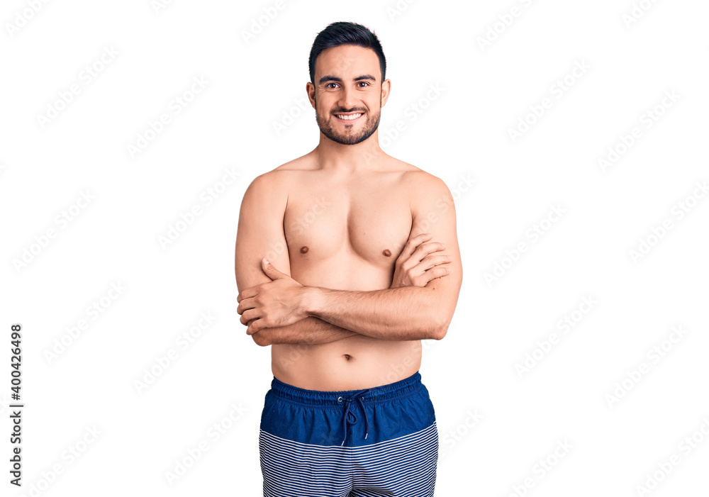 Fototapeta premium Young handsome man wearing swimwear happy face smiling with crossed arms looking at the camera. positive person.