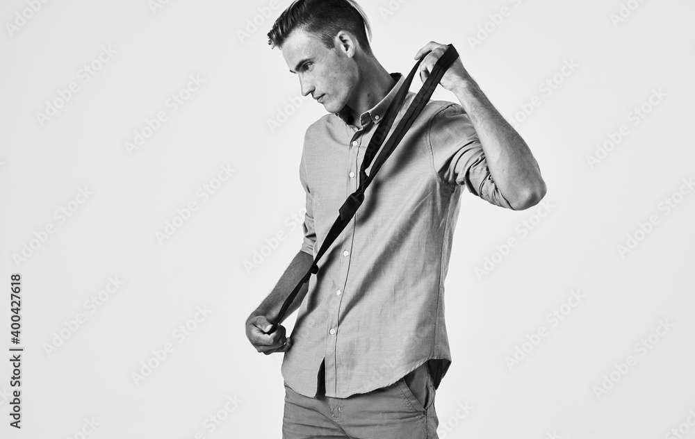 Retro photo of a man in a shirt, tie in hand and light background side view Retro photo of a man in a shirt, tie in hand and light background side view