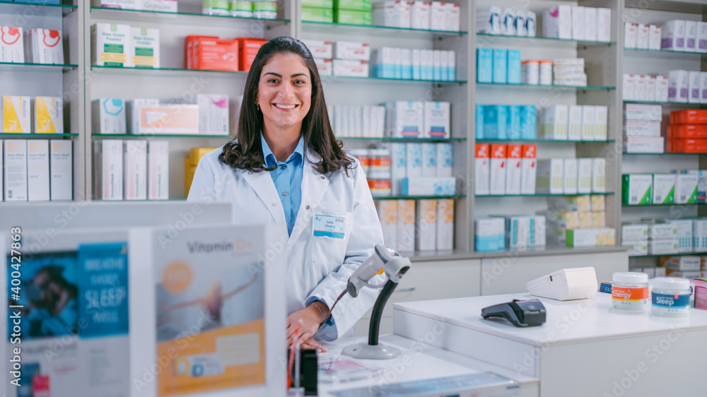 Pharmacy Drugstore Checkout Cashier Counter: Portrait of Beautiful Young Latin Female Pharmacist Looks at the Camera, Smiles Charmingly. Store with Medicine, Drugs, Vitamins, Health Care Products