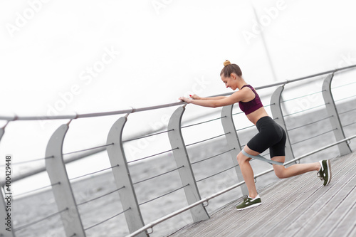 Young fitness woman doing squats with fitness loop band.