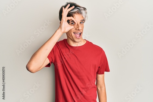 Young hispanic man wearing casual clothes doing ok gesture with hand smiling  eye looking through fingers with happy face.