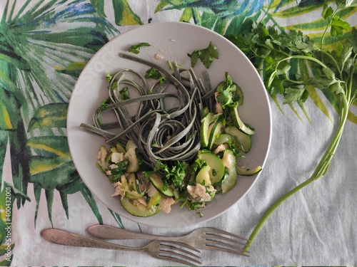Green spirulina algae linguine pasta cooked with salmon, zucchini, persil and a lot of extrevirgin olive oil as atypical mediterranean italian meal. All served in colorful and leaves background