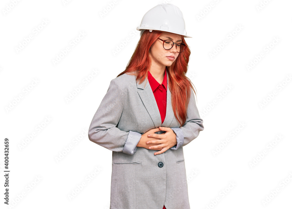 Young redhead woman wearing architect hardhat with hand on stomach because indigestion, painful illness feeling unwell. ache concept.