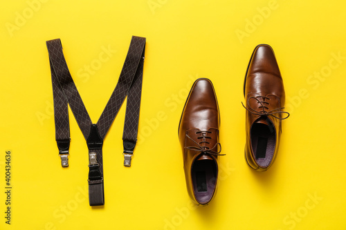 Classic leather male shoes and  suspenders on color background