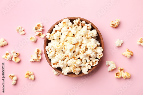Bowl of tasty popcorn on color background