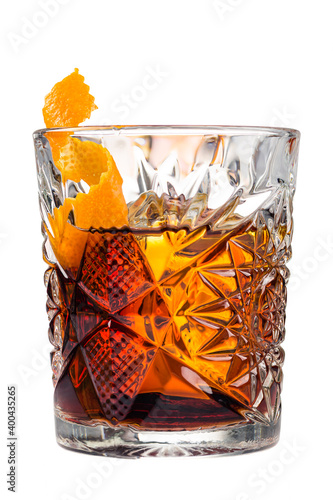 Glass of a Boulevardier cocktail with big ice cube and orange zest, classic cocktail Boozy Boulevardier with Orange and Vermouth isolated on white background photo