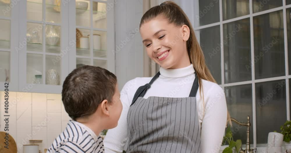 Portrait of cheerful mother laughing with her little son, cooking dinner together at kitchen, slow motion Portrait of cheerful mother laughing with her little son, cooking dinner together at kitchen, slow motion