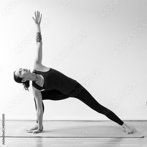 A dark-haired European woman in her 30’s practices yoga at home. Meditation, stretching and mindfulness to achieve physical and spiritual health. Black and white square format