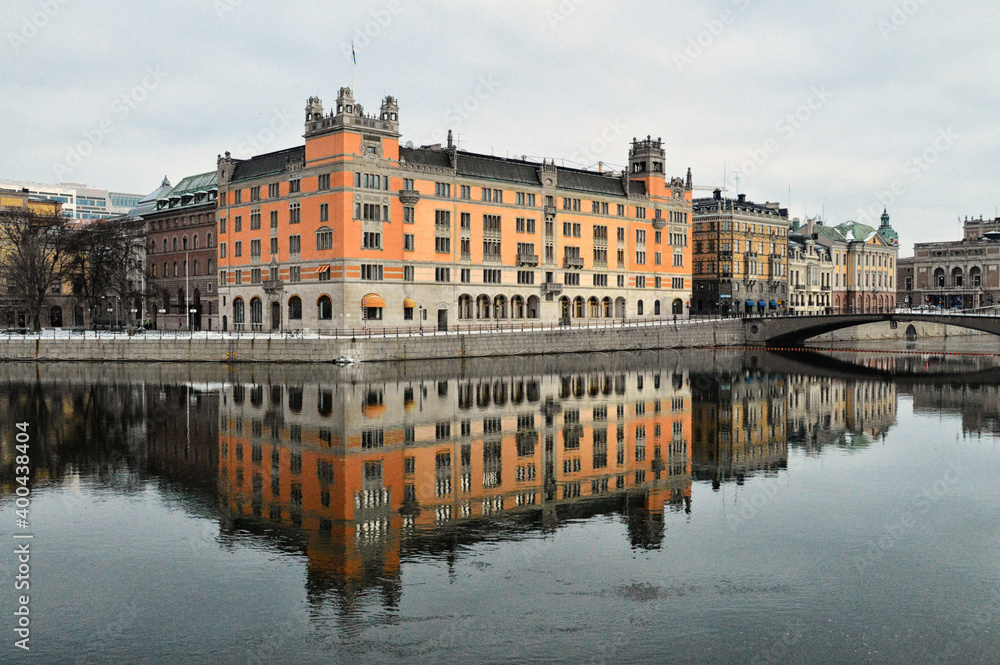 An orange historical building in Stockholm is fully reflected in the river