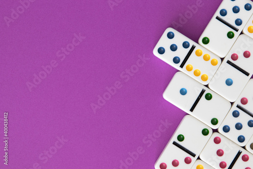 Obraz na plátně Colorful dominoes arranged on purple background with negative space for copy