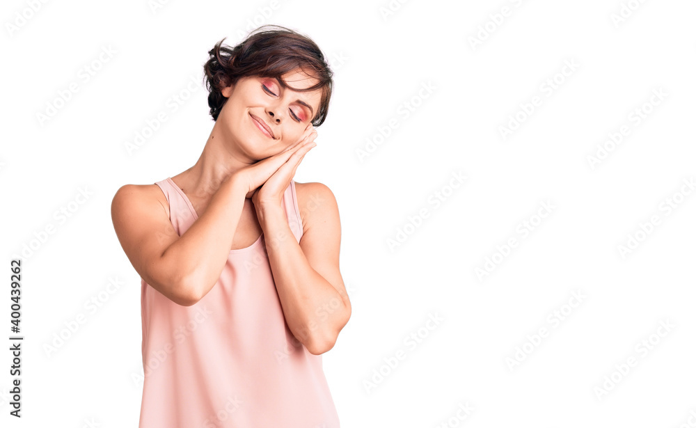 Beautiful young woman with short hair wearing casual style with sleeveless shirt sleeping tired dreaming and posing with hands together while smiling with closed eyes. Beautiful young woman with short hair wearing casual style with sleeveless shirt sleeping tired dreaming and posing with hands together while smiling with closed eyes.