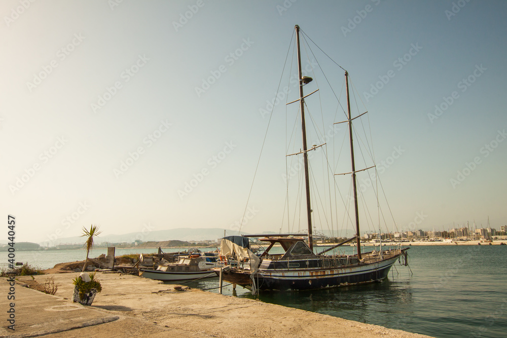 Abandoned sailing vessel moored on Athens pier in sunny day. Greece.