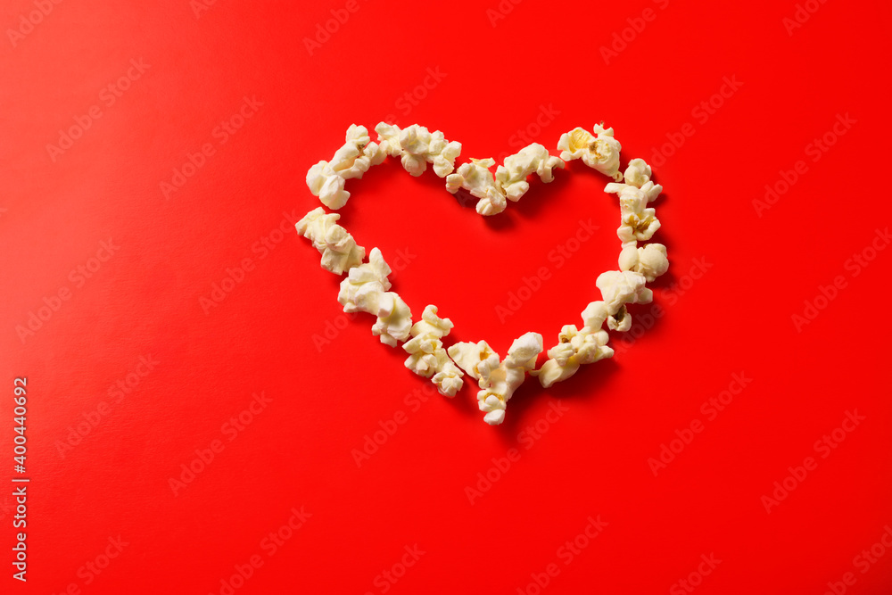 Popcorn is laid out in the shape of a heart on a red background. Blank for valentine.