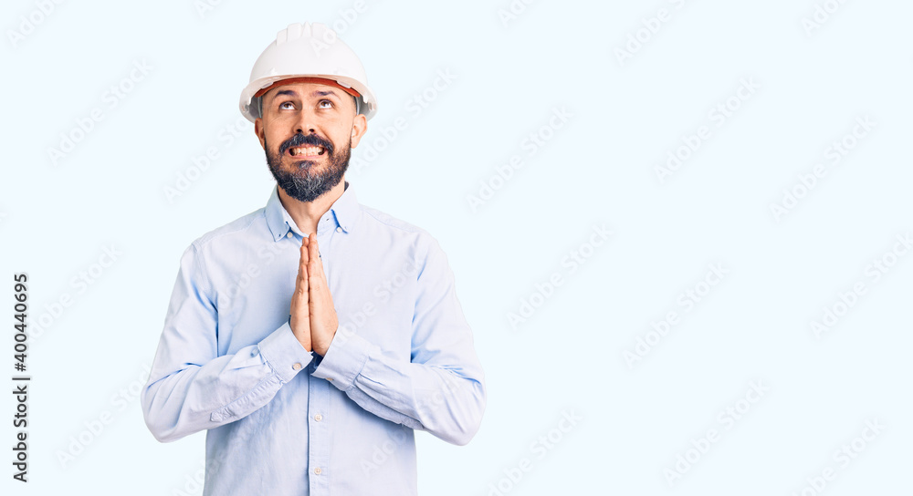 Young handsome man wearing architect hardhat begging and praying with hands together with hope expression on face very emotional and worried. begging. Young handsome man wearing architect hardhat begging and praying with hands together with hope expression on face very emotional and worried. begging.