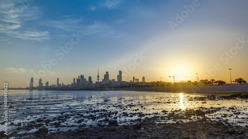 Seaside skyline of Kuwait city sunrise timelapse. Modern towers and skyscrapers reflected in water. photo