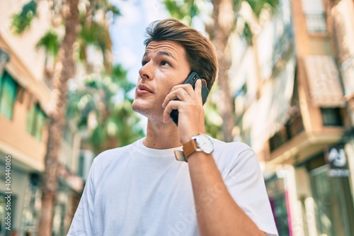 Young caucasian man with serious expression talking on the smartphone at the city. © Krakenimages.com
