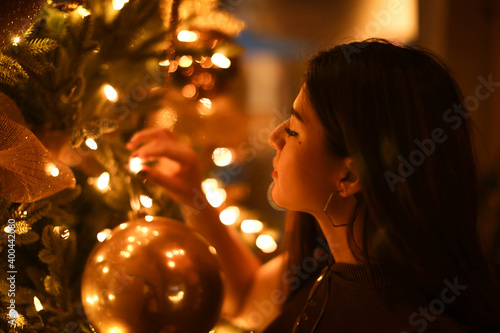 Girl touching ligth by christmas tree
