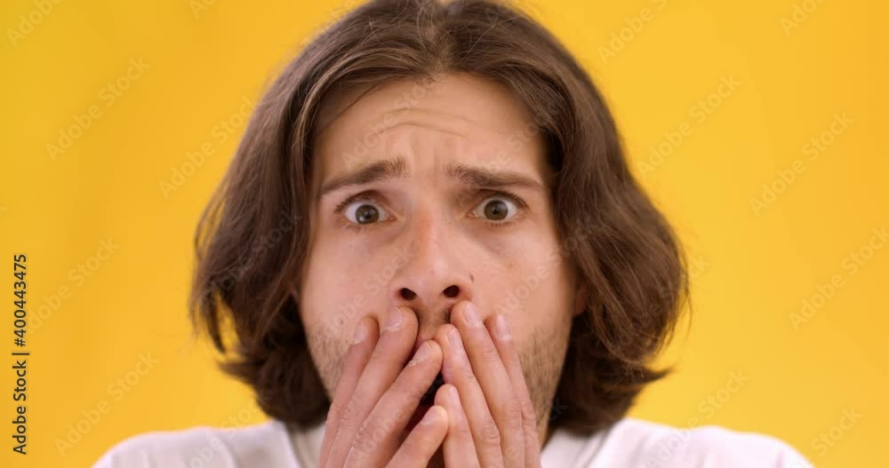 Close up portrait of young man feeling excited and amazed, opening eyes widely and covering mouth, slow motion Close up portrait of young man feeling excited and amazed, opening eyes widely and covering mouth, slow motion