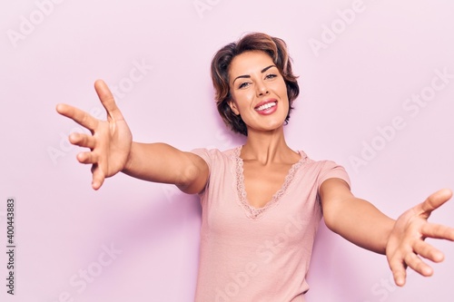 Young beautiful woman wearing casual clothes looking at the camera smiling with open arms for hug. cheerful expression embracing happiness.