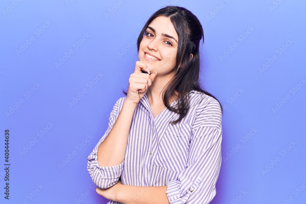 Young beautiful girl wearing casual striped shirt smiling looking confident at the camera with crossed arms and hand on chin. thinking positive. Young beautiful girl wearing casual striped shirt smiling looking confident at the camera with crossed arms and hand on chin. thinking positive.