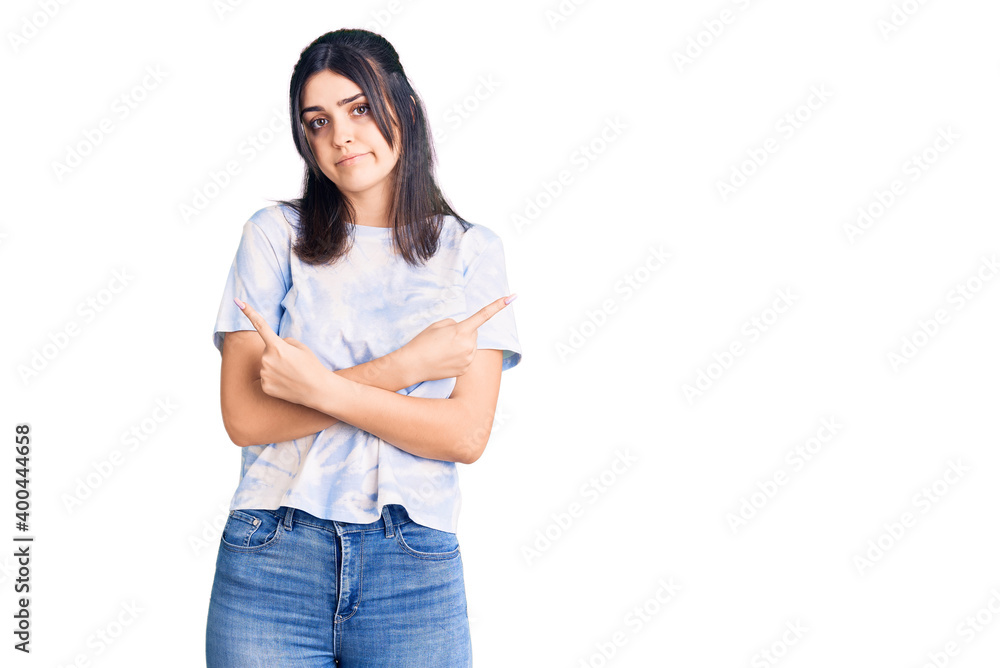 Young beautiful girl wearing casual t shirt pointing to both sides with fingers, different direction disagree Young beautiful girl wearing casual t shirt pointing to both sides with fingers, different direction disagree