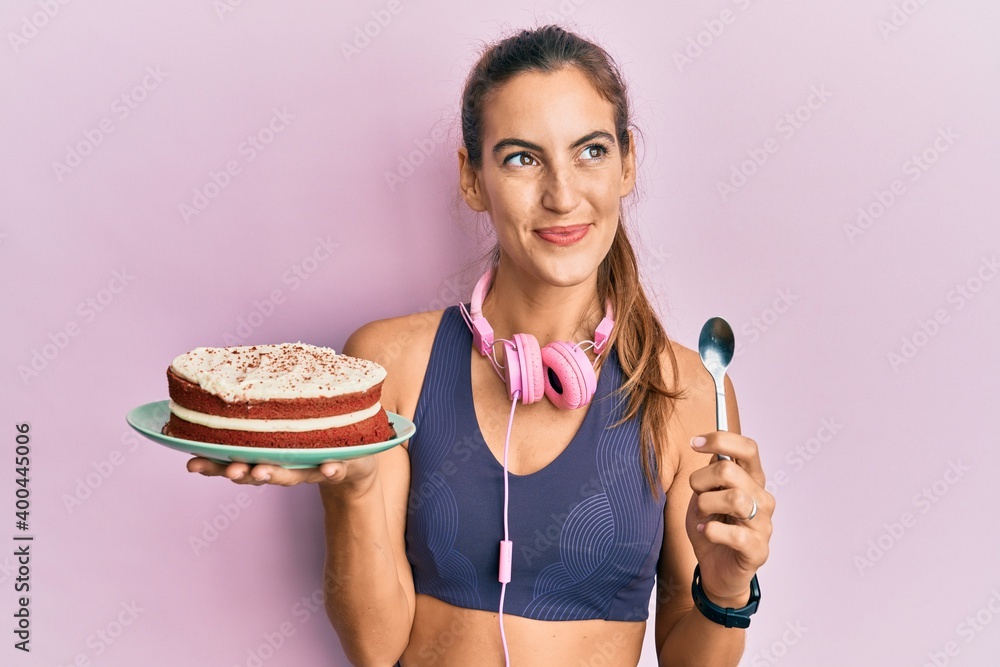 Young beautiful woman wearing gym clothes holding carrot cake smiling looking to the side and staring away thinking. Young beautiful woman wearing gym clothes holding carrot cake smiling looking to the side and staring away thinking.