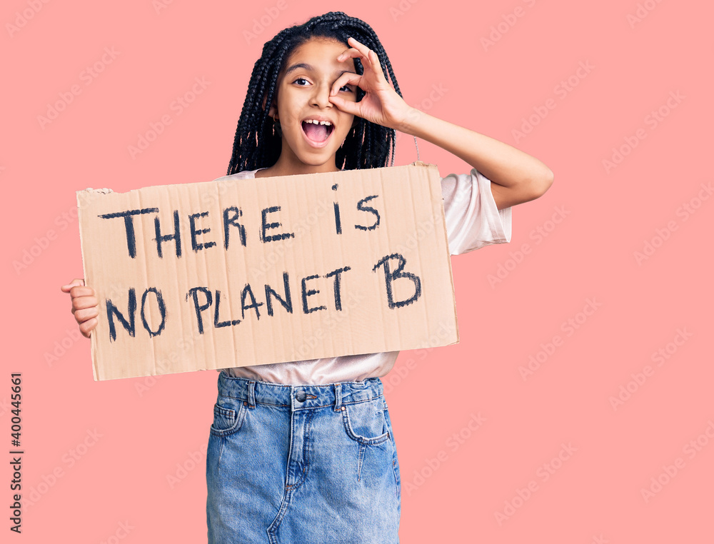 Cute african american girl holding there is no planet b banner smiling happy doing ok sign with hand on eye looking through fingers Cute african american girl holding there is no planet b banner smiling happy doing ok sign with hand on eye looking through fingers