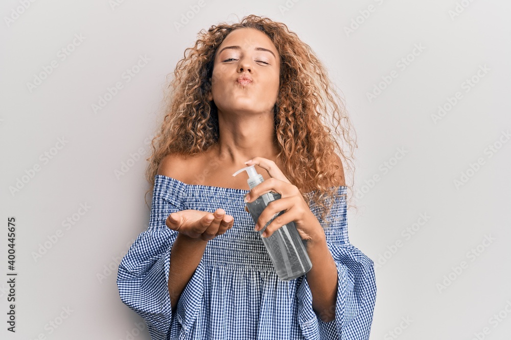 Beautiful caucasian teenager girl using hand sanitizer gel looking at the camera blowing a kiss being lovely and sexy. love expression. Beautiful caucasian teenager girl using hand sanitizer gel looking at the camera blowing a kiss being lovely and sexy. love expression.