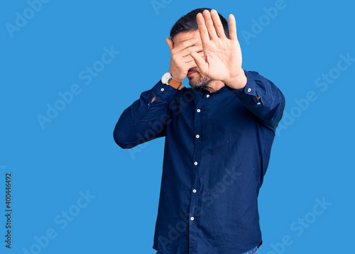 Young handsome man wearing casual shirt covering eyes with hands and doing stop gesture with sad and fear expression. embarrassed and negative concept. photo