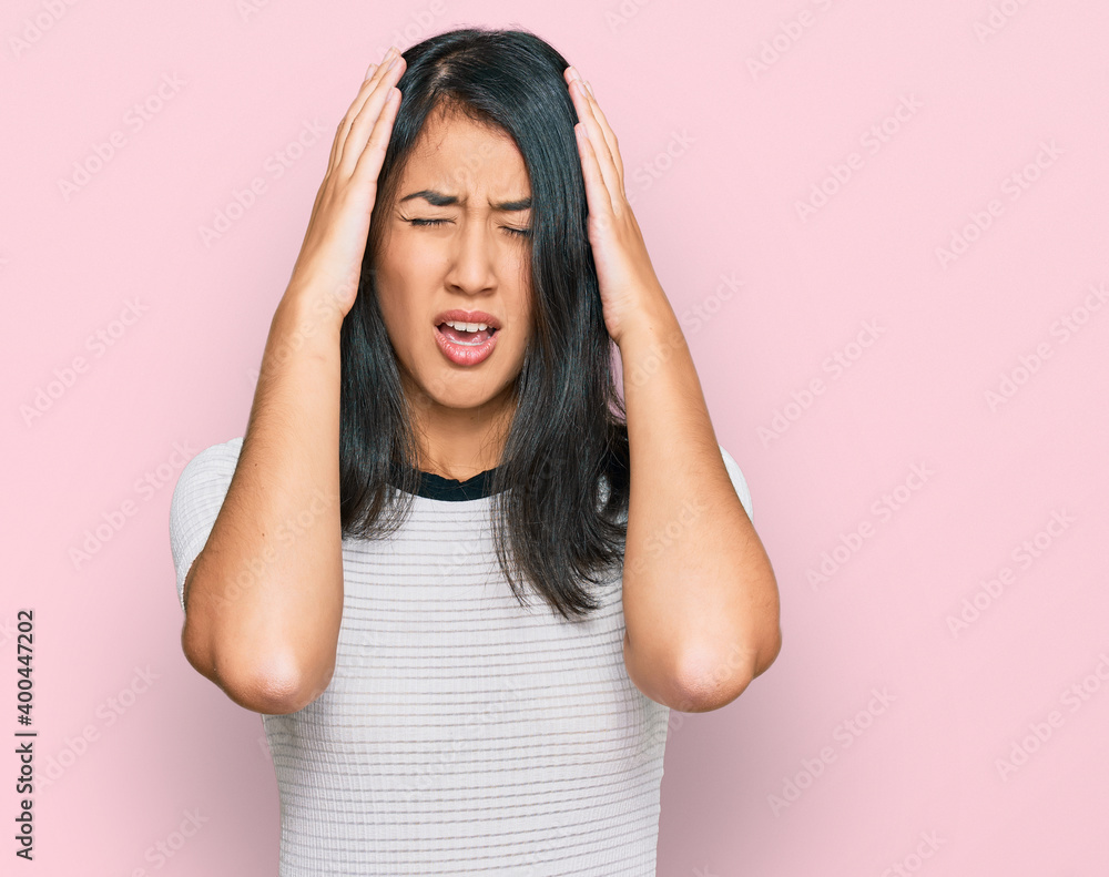 Beautiful asian young woman wearing casual white t shirt suffering from headache desperate and stressed because pain and migraine. hands on head. Beautiful asian young woman wearing casual white t shirt suffering from headache desperate and stressed because pain and migraine. hands on head.