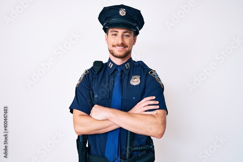 Canvas Print Young caucasian man wearing police uniform happy face smiling with crossed arms looking at the camera