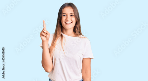 Beautiful caucasian woman wearing casual white tshirt showing and pointing up with finger number one while smiling confident and happy.